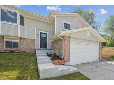 Charming gray two-story home featuring brick accents, fresh landscaping, and a convenient two-car garage at 3247 S Newland St, Denver, CO 80227