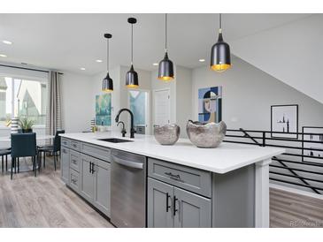 Modern kitchen island with quartz countertops, stylish pendant lights, stainless steel appliances, and gray cabinetry at 10866 Lyric St, Lone Tree, CO 80134