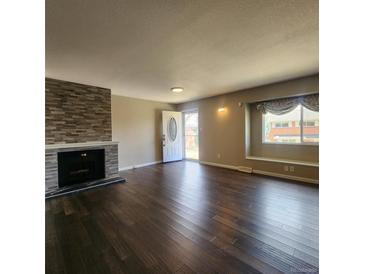 Inviting living room boasts a stone fireplace, wood floors, and a bright window seat at 9017 E Oxford Dr, Denver, CO 80237