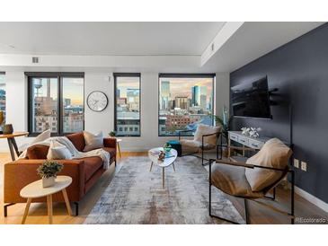 Inviting living room featuring expansive windows showcasing beautiful city views and hardwood floors at 1750 Wewatta St # 830, Denver, CO 80202