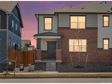 Charming two-story home with gray siding, brick accents, and a well-manicured front yard under a lovely colorful sunset sky at 383 Remuda Rd, Berthoud, CO 80513