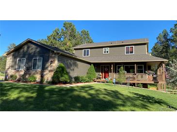 Charming two-story home featuring a welcoming front porch, lush lawn, and mature trees, creating a serene curb appeal at 35550 Running Brook Ln, Elizabeth, CO 80107