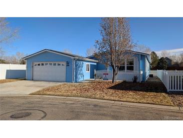 Cute blue house with white fence and a two-car garage at 7982 Larkspur Cir, Frederick, CO 80530