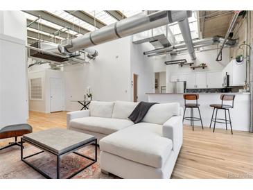 Bright, open living space with white sofa, hardwood floors, and modern industrial design at 2020 Arapahoe St # 1250, Denver, CO 80205