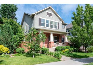 Charming two-story home featuring manicured lawn, brick accents, and inviting front porch at 817 Uinta Way, Denver, CO 80230