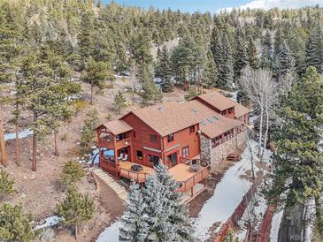 Stunning aerial view of a multi-story home with a deck nestled in a lush forest setting at 29477 Blue Moon Dr, Evergreen, CO 80439