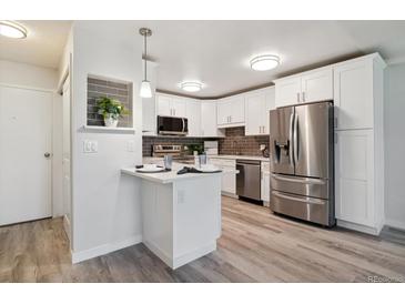 Bright kitchen features stainless steel appliances, white cabinetry, gray backsplash and stylish breakfast bar at 715 S Alton Way # 5A, Denver, CO 80247