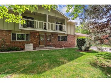 Inviting two-story brick home featuring charming balconies and a lush green lawn at 372 Vance St, Lakewood, CO 80226