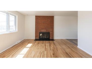 Bright living room with a brick fireplace and hardwood flooring at 785 Planet Pl, Thornton, CO 80260