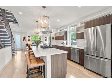 Bright, modern kitchen with stainless steel appliances, large island, and hardwood floors at 3612 Wyandot St, Denver, CO 80211