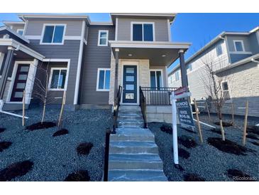 Modern two-story townhome featuring stone accents, a covered entryway, and a professionally landscaped front yard at 22792 E Tufts Ave # A, Aurora, CO 80015