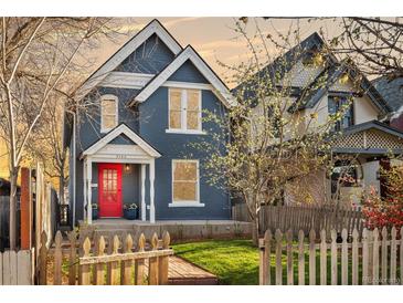 Charming two-story home with blue siding, white trim, a red door and a lovely landscaped yard at 3142 W 26Th Ave, Denver, CO 80211