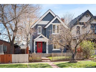 Charming two-story home with a red door, quaint picket fence, and well-manicured lawn at 3142 W 26Th Ave, Denver, CO 80211