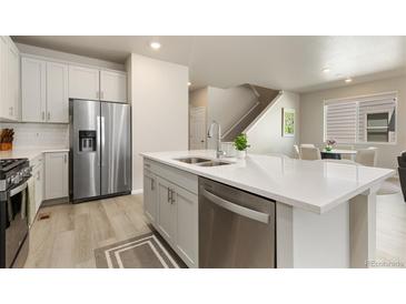 Modern kitchen featuring a stainless steel refrigerator and an island with a sink at 6150 Sugarloaf St, Brighton, CO 80601