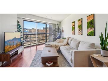 Bright living room featuring a modern sofa, hanging chair, and a sliding glass door with balcony access at 100 Park W Ave # 304, Denver, CO 80205