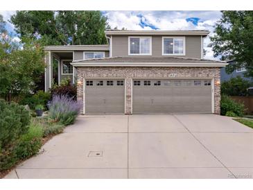 Two-story home features a two-car garage, brick accents, manicured front yard with mature trees and beautiful landscaping at 9170 Fox Fire Dr, Highlands Ranch, CO 80129