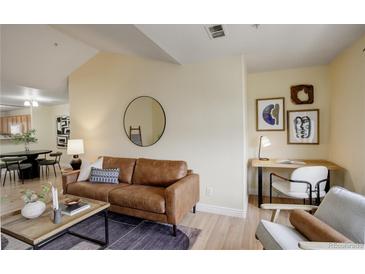 Comfortable living room with a supple brown leather sofa, desk, and a round mirror on a modern wall at 12281 E Tennessee Dr # 302, Aurora, CO 80012