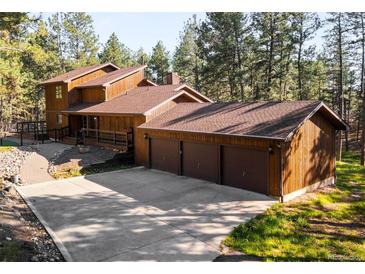 Charming wooden home featuring a three-car garage and a lush, forested surrounding at 612 Nob Hill Trl, Franktown, CO 80116