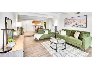 A bright living room with hardwood floors, green sofas, a round table, and a desert-themed painting at 8060 E Girard Ave # 311, Denver, CO 80231