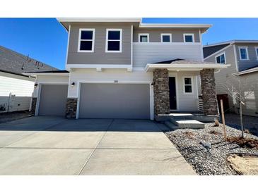 Charming two-story home featuring stone accents, a two-car garage, and a well-manicured front yard at 210 Lark Sparrow Way, Bennett, CO 80102