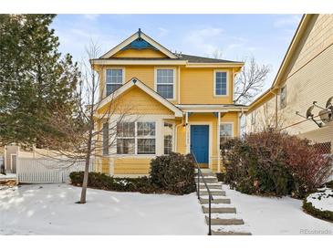 Beautiful two-story yellow house with a blue door and snowy front yard at 1503 S Buckley Way, Aurora, CO 80017