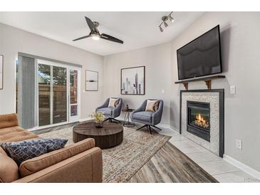 Bright living room with fireplace, hardwood floors, and sliding glass door to patio at 8757 E Dry Creek Rd # 1512, Englewood, CO 80112