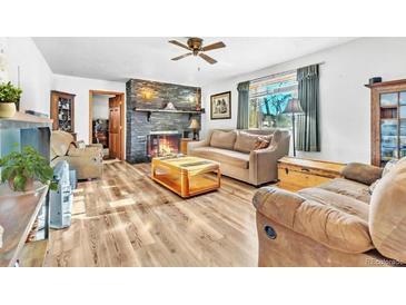 Inviting living room with a stone fireplace, wood floors, and neutral-colored sofas at 11953 Us Highway 285, Conifer, CO 80433