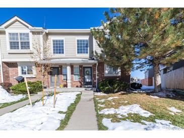 Beige townhouse exterior with brick accents, a small front yard, and walkway at 1214 S Zeno Way # D, Aurora, CO 80017