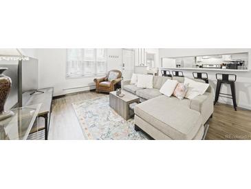 Inviting living room with a comfortable gray sectional couch and view to the kitchen bar seating at 677 Vrain St # 15, Denver, CO 80204