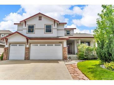 Two-story home featuring a three-car garage, brick accents, well manicured lawn, and classic architectural details at 10683 Amesbury Way, Highlands Ranch, CO 80126