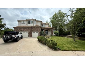 Charming two-story home with brick accents, a three-car garage, and a well-manicured front yard at 7858 Oban Ct, Lone Tree, CO 80124