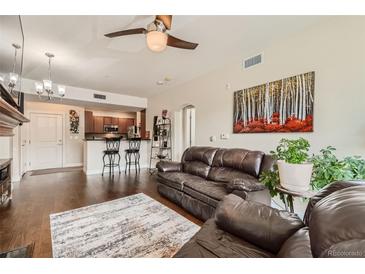 Cozy living room features wood floors, ceiling fan, and access to the kitchen at 9019 E Panorama Cir # D207, Englewood, CO 80112