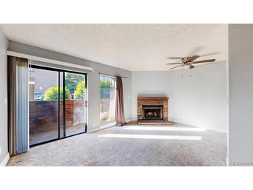 Bright living room with sliding glass doors and a cozy brick fireplace at 12360 W Nevada Pl # 101, Lakewood, CO 80228