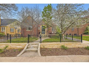 Charming brick home with a manicured front yard, a stone wall, and a wrought iron fence showcasing curb appeal at 944 S Euclid Way, Denver, CO 80209