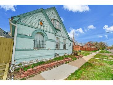 Charming light blue home with unique architectural details and a small, quaint brick-lined garden at 1930 E Martin Luther King Jr Blvd, Denver, CO 80205