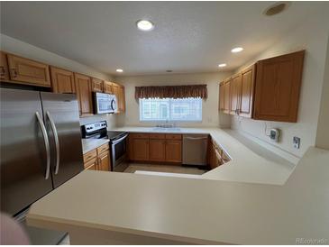 Well-lit kitchen with stainless steel appliances and a breakfast bar that opens to the living area at 10129 Grove Ct # B, Westminster, CO 80031