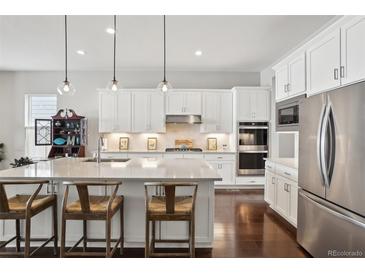 Modern white kitchen featuring stainless steel appliances, a large central island, and sleek countertops for culinary enthusiasts at 5622 Shadescale Way, Castle Rock, CO 80104