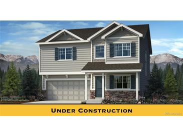 Charming two-story home with gray siding, stone accents, and a two-car garage, all set against a backdrop of mountains at 716 N Carrie Ct, Watkins, CO 80137