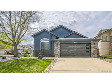 Charming blue home featuring a modern garage, stone accents, and manicured lawn at 12133 Crabapple St, Broomfield, CO 80020