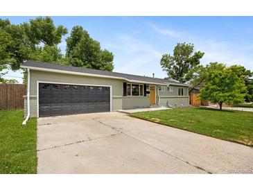 Charming single-story home featuring a well-maintained lawn, a dark gray garage door, and fresh light-green paint at 1205 W 101St Ave, Northglenn, CO 80260