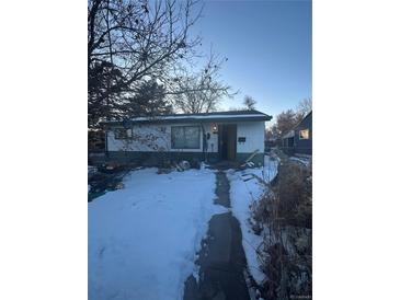 View of a snow-covered front yard leading to a single-story home with white brick and dark green trim at 925 Quitman St, Denver, CO 80204