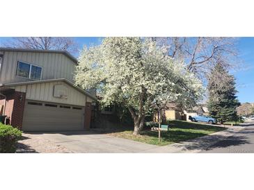 Charming home featuring a well-maintained front yard, a two-car garage, and beautiful flowering tree at 12682 W Louisiana Ave, Lakewood, CO 80228