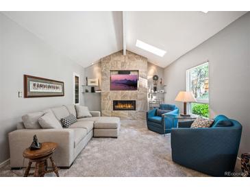 Bright living room featuring vaulted ceilings, stone fireplace and comfortable seating at 7414 S Monroe Ct, Centennial, CO 80122