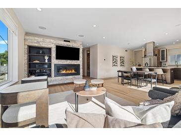 Bright living room with hardwood floors, stone fireplace, built in shelving, and an open floor plan to the kitchen at 3615 Navajo St, Denver, CO 80211
