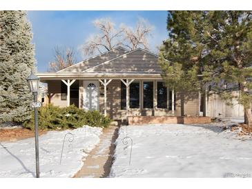 Ranch style home with covered porch and snow-covered yard at 2610 S Vine St, Denver, CO 80210