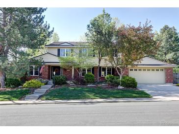 Traditional two-story home with well-maintained lawn and mature trees on a sunny day at 10886 E Berry Ave, Englewood, CO 80111