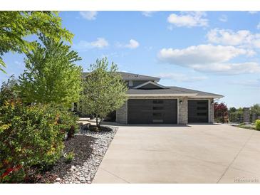 Beautiful home featuring a stone exterior, three-car garage, and a wide driveway surrounded by lush greenery at 14712 Kalamath Ct, Westminster, CO 80023