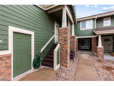 Green townhome exterior with stone accents, private entrance, and well-maintained walkway at 19437 E Mann Creek Dr # A, Parker, CO 80134