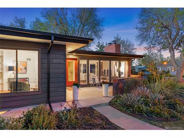 Charming single-story home with a red door, large windows, and a beautifully landscaped front yard at 8955 E 19Th Ave, Aurora, CO 80010