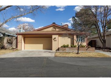 Tan home features an attached two-car garage, manicured front yard, and a brick retaining wall with a red trim at 3333 E Florida Ave # 108, Denver, CO 80210